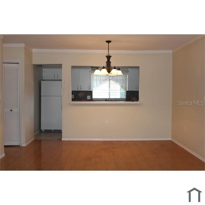 A dining area with wood-look flooring features a pass-through window looking into a kitchen — 8605 CHAMPLAIN COURT UNIT 84, TAMPA, FL