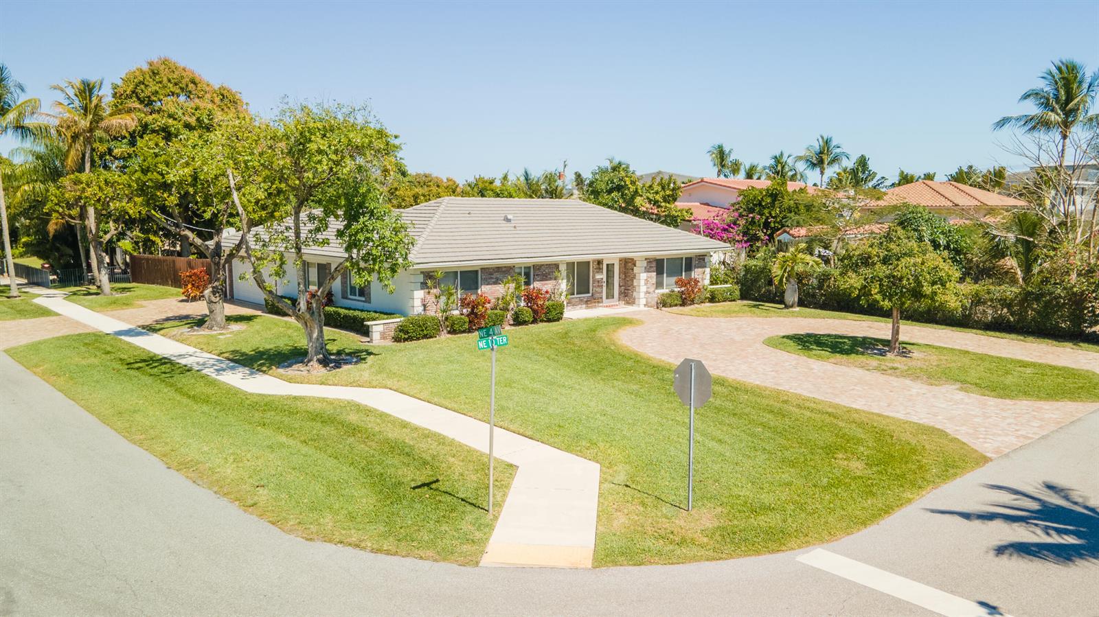 A single-story house with a brick facade and a paved driveway sits on a corner lot — 401 NE 10th Terrace, Boca Raton FL 33432, BOCA RATON, FL