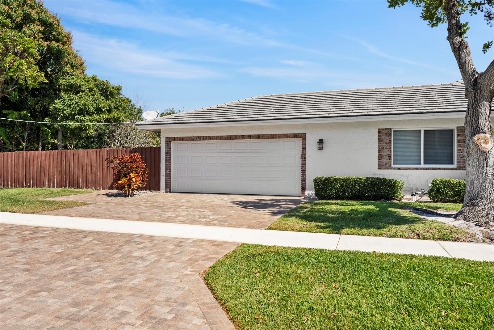 A white house with a brick-trimmed garage and a paved driveway under a blue sky — 401 NE 10th Terrace, Boca Raton FL 33432, BOCA RATON, FL