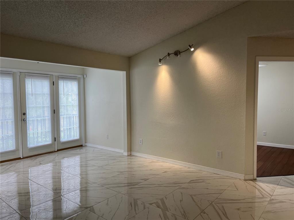 A room with white marble-patterned tile flooring, a track light fixture, and glass patio doors — 232 AFTON SQUARE UNIT 201, ALTAMONTE SPRINGS, FL