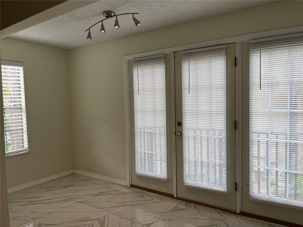 A room with white marble-patterned tile floors, a track light fixture, and glass-paned double doors — 232 AFTON SQUARE UNIT 201, ALTAMONTE SPRINGS, FL
