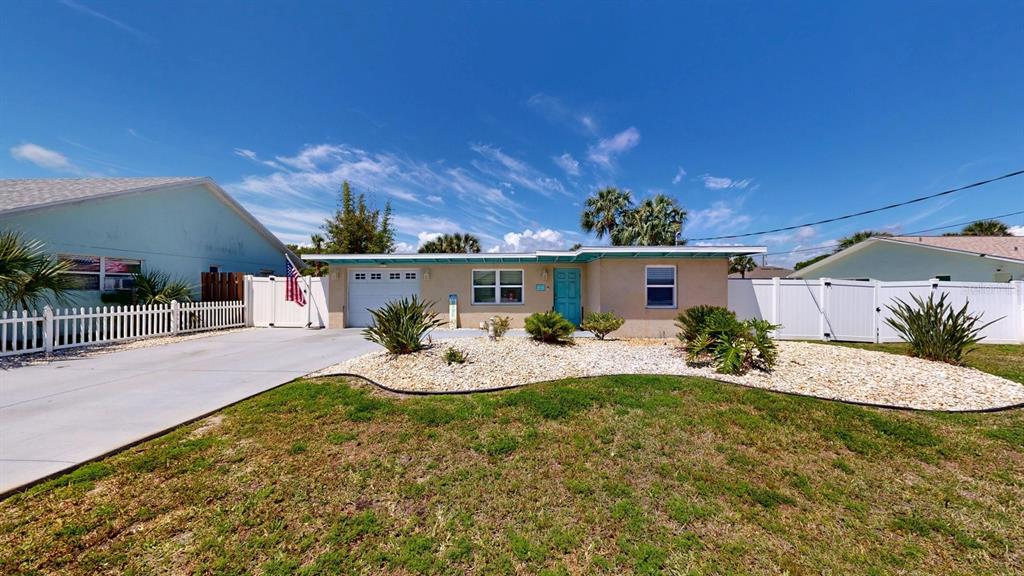 A single-story house with a white garage, blue front door, and a gravel front yard — 119 N PALMETTO AVENUE, FLAGLER BEACH, FL