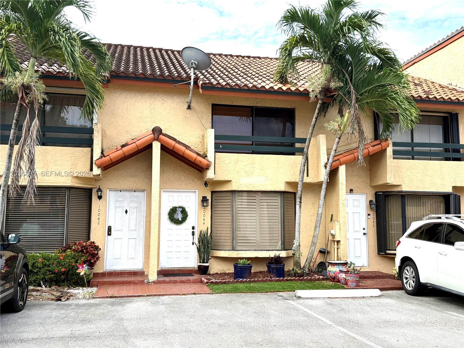 A row of two-story townhouses with beige stucco walls, tile roofs, and palm trees in front — 10044 SW 77th Ct # 0, Miami FL 33156, MIAMI, FL