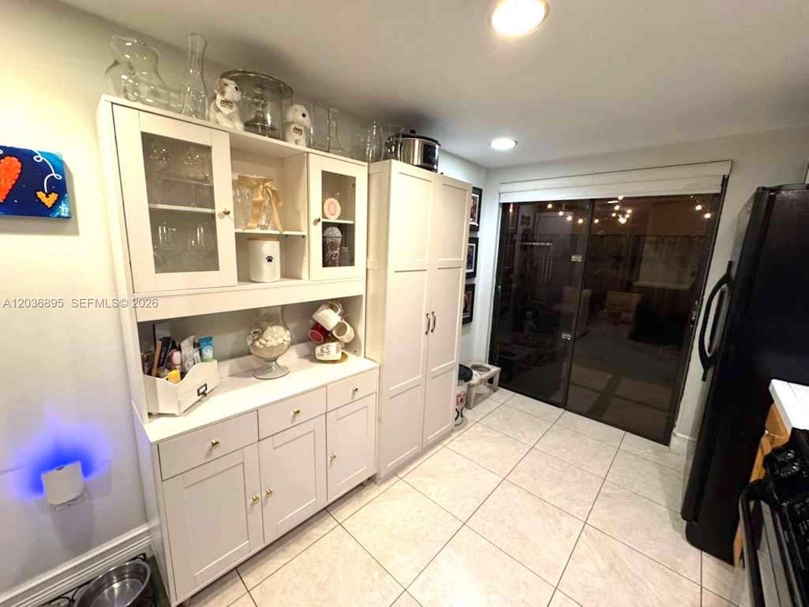 A kitchen features white cabinetry, a hutch, tiled floors, and a sliding glass door — 10044 SW 77th Ct # 0, Miami FL 33156, MIAMI, FL