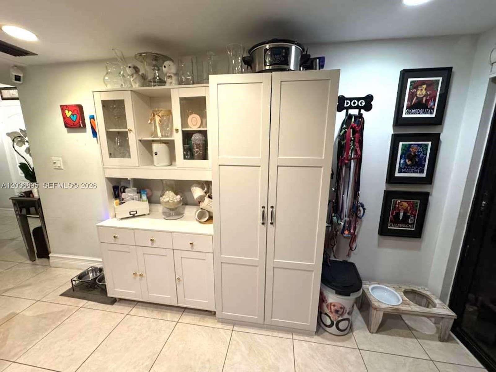 A kitchen or dining area features white cabinetry, a tall pantry, and pet-related decor — 10044 SW 77th Ct # 0, Miami FL 33156, MIAMI, FL
