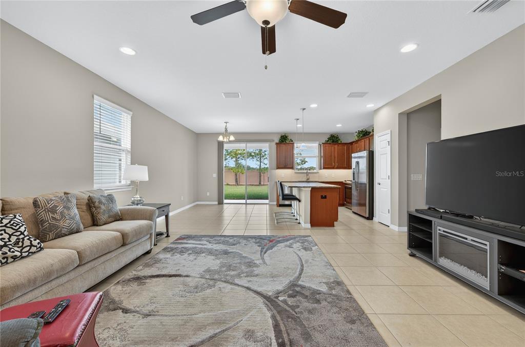 An open-concept living room and kitchen featuring tile floors, a ceiling fan, and sliding doors — 3947 NW 46TH TERRACE, OCALA, FL
