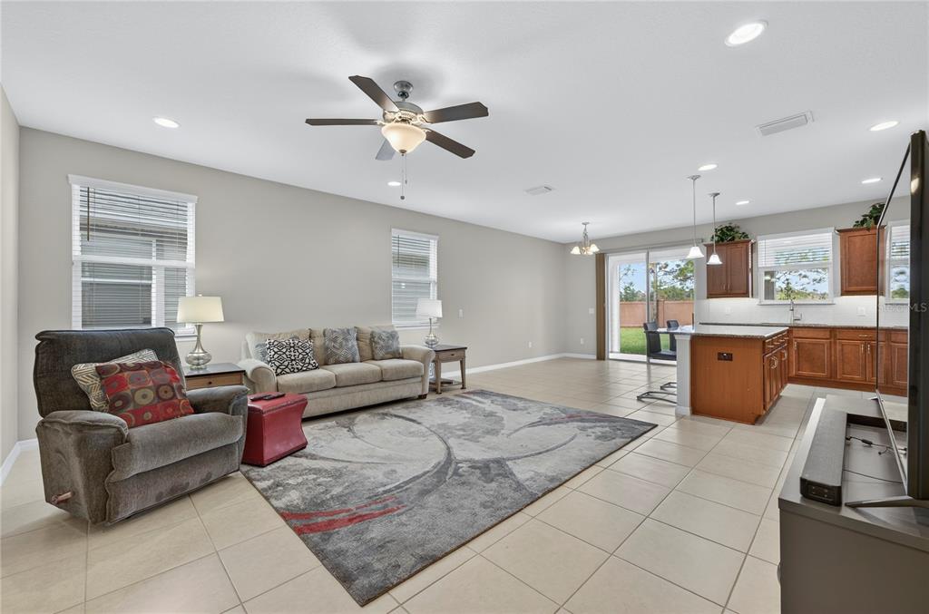 An open-concept living room and kitchen featuring tile floors, a ceiling fan, and neutral walls — 3947 NW 46TH TERRACE, OCALA, FL