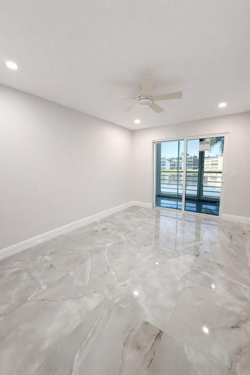 An empty room with light gray walls, large marble-look floor tiles, and a sliding glass door — 2019 Wolverton A, Boca Raton FL 33434, BOCA RATON, FL