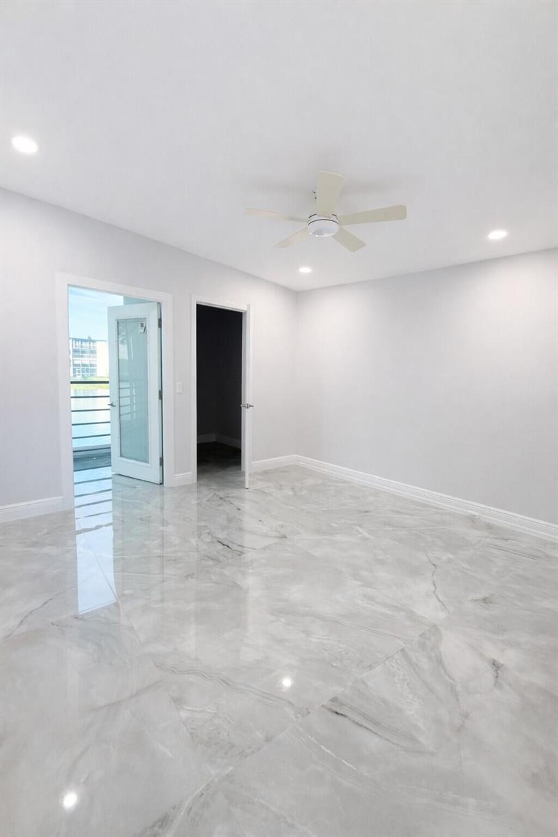 A bright room features glossy marble-look tile flooring, a ceiling fan, and a glass balcony door — 2019 Wolverton A, Boca Raton FL 33434, BOCA RATON, FL