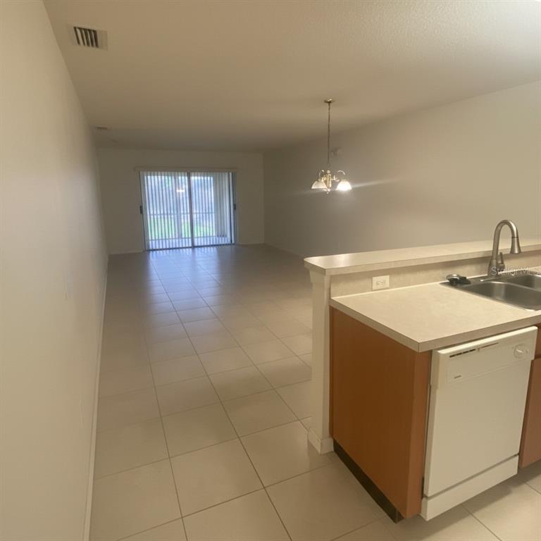 An open-concept living and dining area features light tile flooring and a kitchen breakfast bar — 2150 MYSTIC RING LOOP, KISSIMMEE, FL
