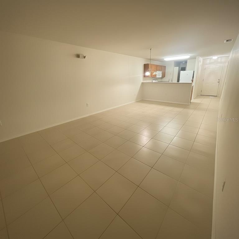 An open-concept living area features light-colored tile flooring and a kitchen with a breakfast bar — 2150 MYSTIC RING LOOP, KISSIMMEE, FL