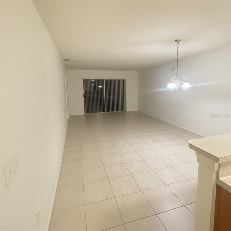 An open-concept living and dining area features light-colored floor tiles and a sliding glass door — 2150 MYSTIC RING LOOP, KISSIMMEE, FL