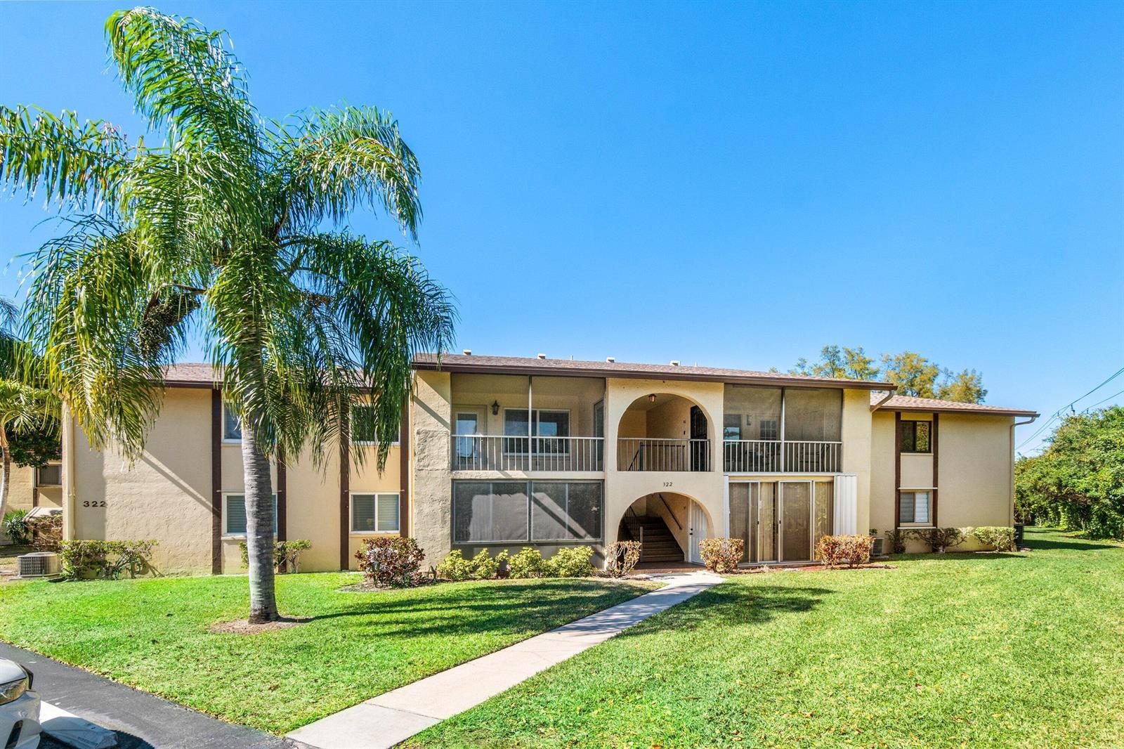 A two-story apartment building with a palm tree, screened balconies, and a concrete walkway — 322 Pine Ridge Circle # 2, FL 33463, FL