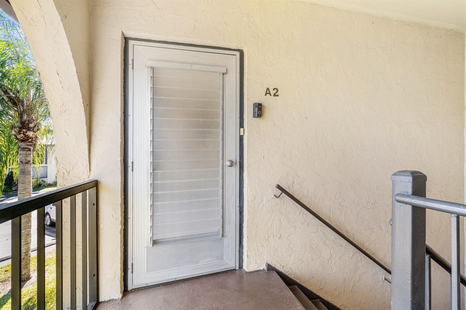 An exterior view shows a white storm door labeled A2 with a handrail and stairs — 322 Pine Ridge Circle # 2, FL 33463, FL