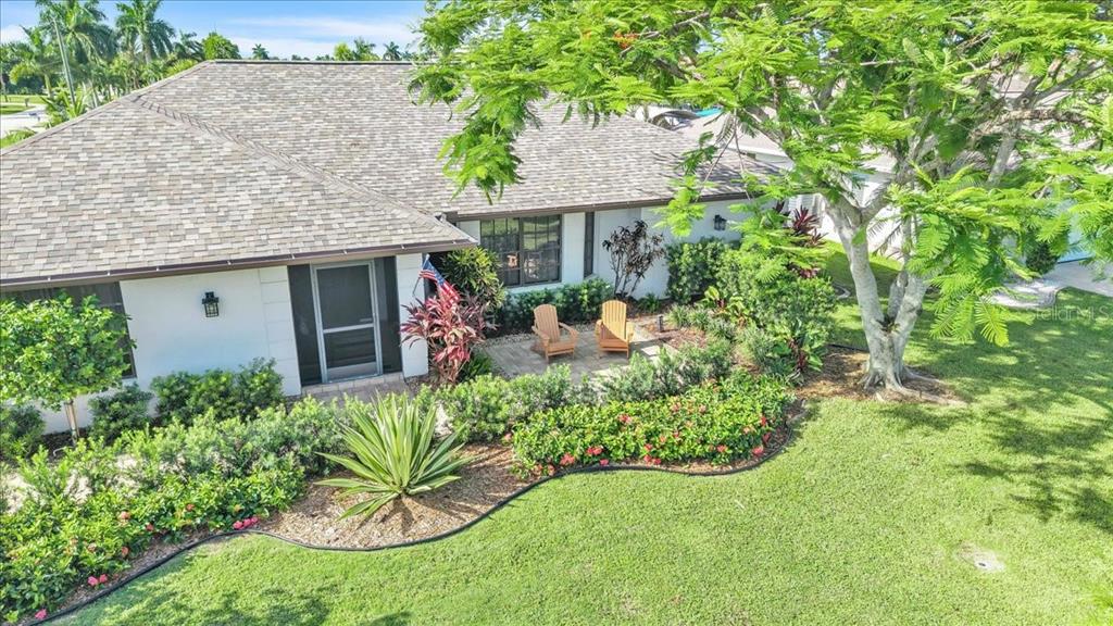 An aerial view of a house exterior featuring a front patio with two wooden chairs — 1903 SE 29TH LANE, CAPE CORAL, FL
