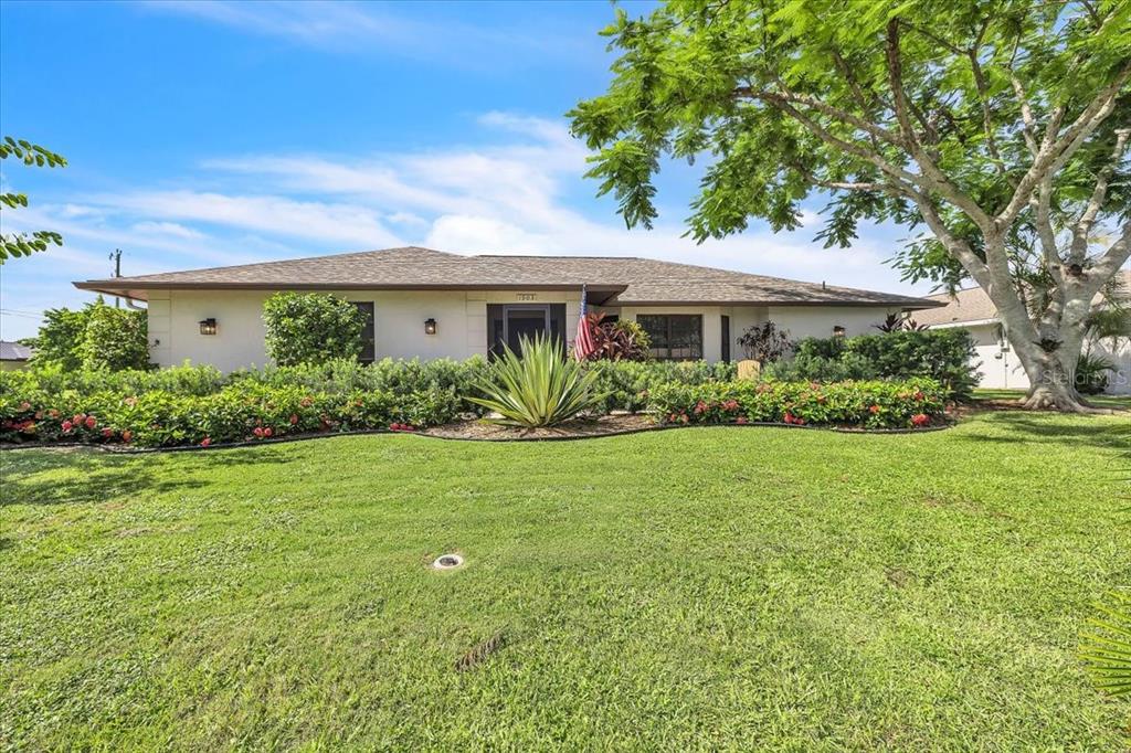 A single-story house with a lawn, landscaping, and a large tree in the front yard — 1903 SE 29TH LANE, CAPE CORAL, FL