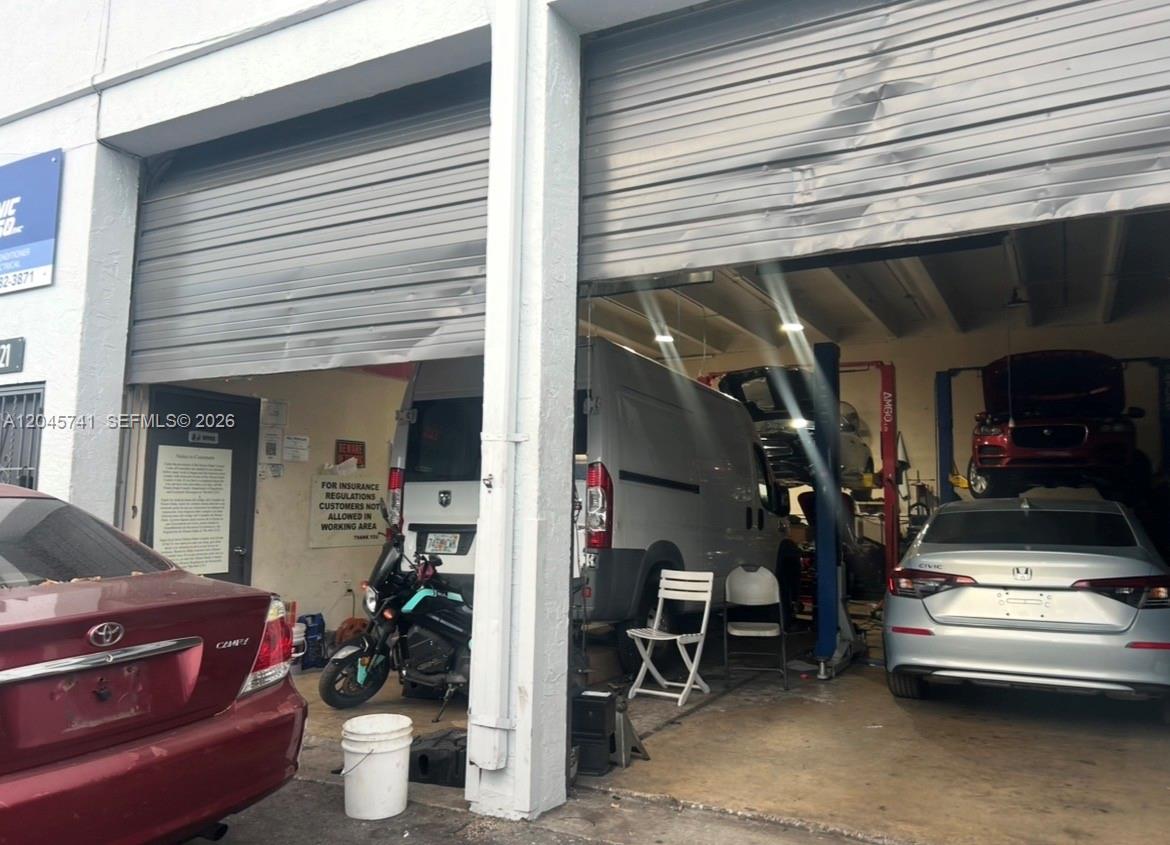 An auto repair shop with an open garage door showing vehicles parked inside — 7601 NW 68th St, Miami FL 33166, MIAMI, FL