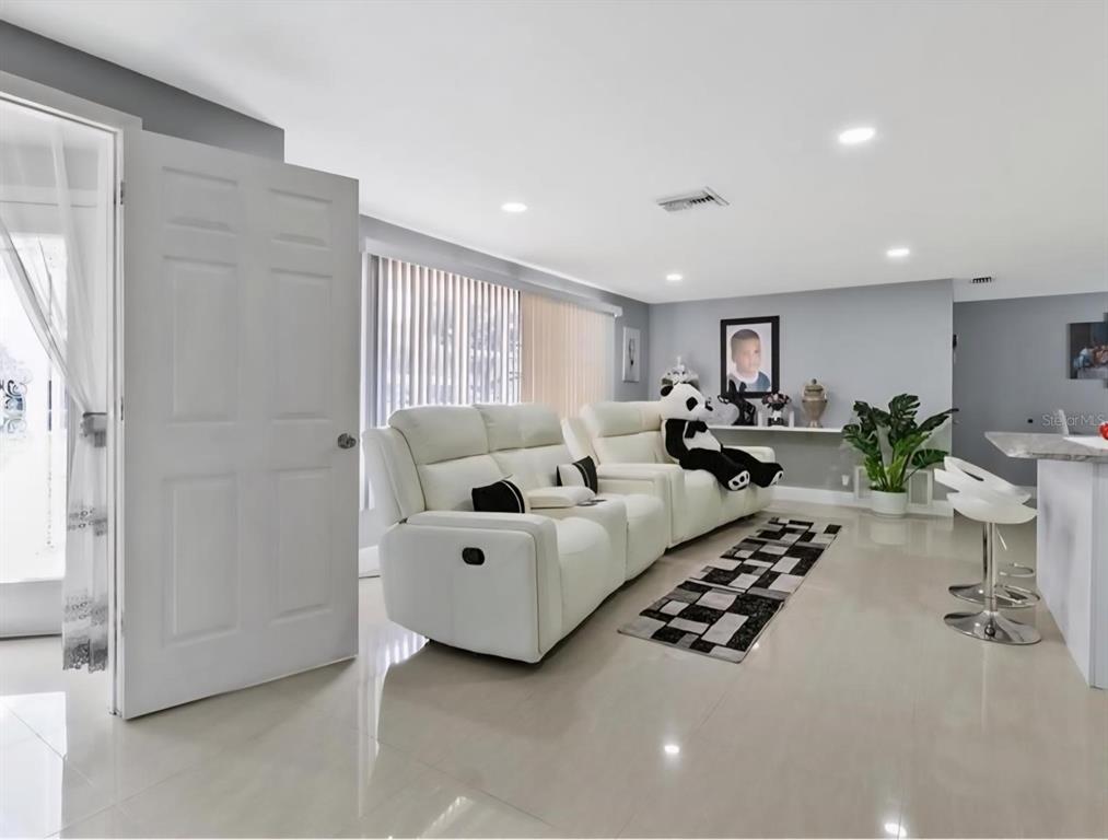 A living room features white reclining sofas, a patterned rug, and light-colored tile flooring — 8310 PAT BOULEVARD, TAMPA, FL