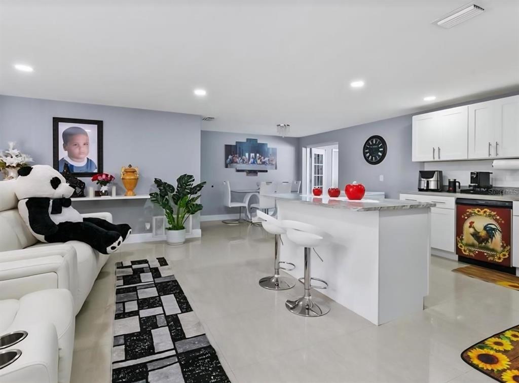An open-concept kitchen and living area features white cabinetry, a central island, and tile flooring — 8310 PAT BOULEVARD, TAMPA, FL