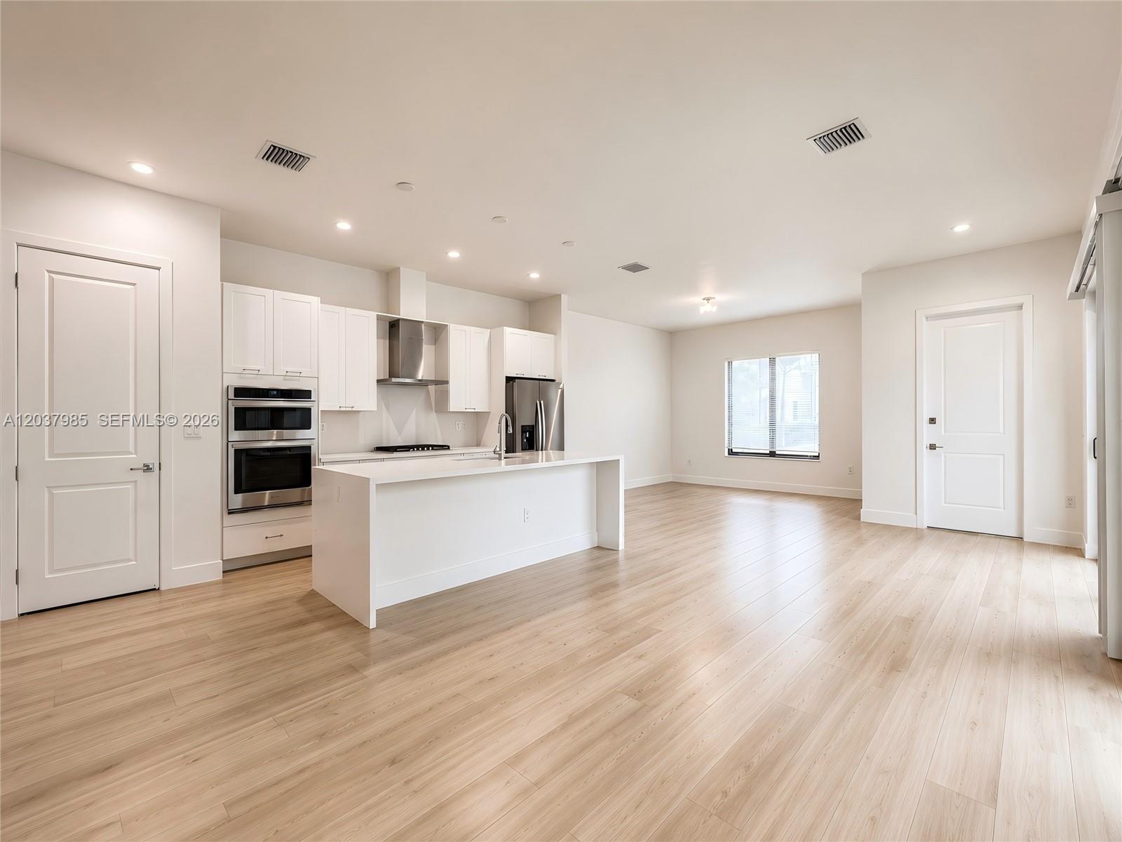 A modern kitchen features white cabinetry, stainless steel appliances, and a central island — 8185 NW 42nd St # 8185, Doral FL 33166, DORAL, FL