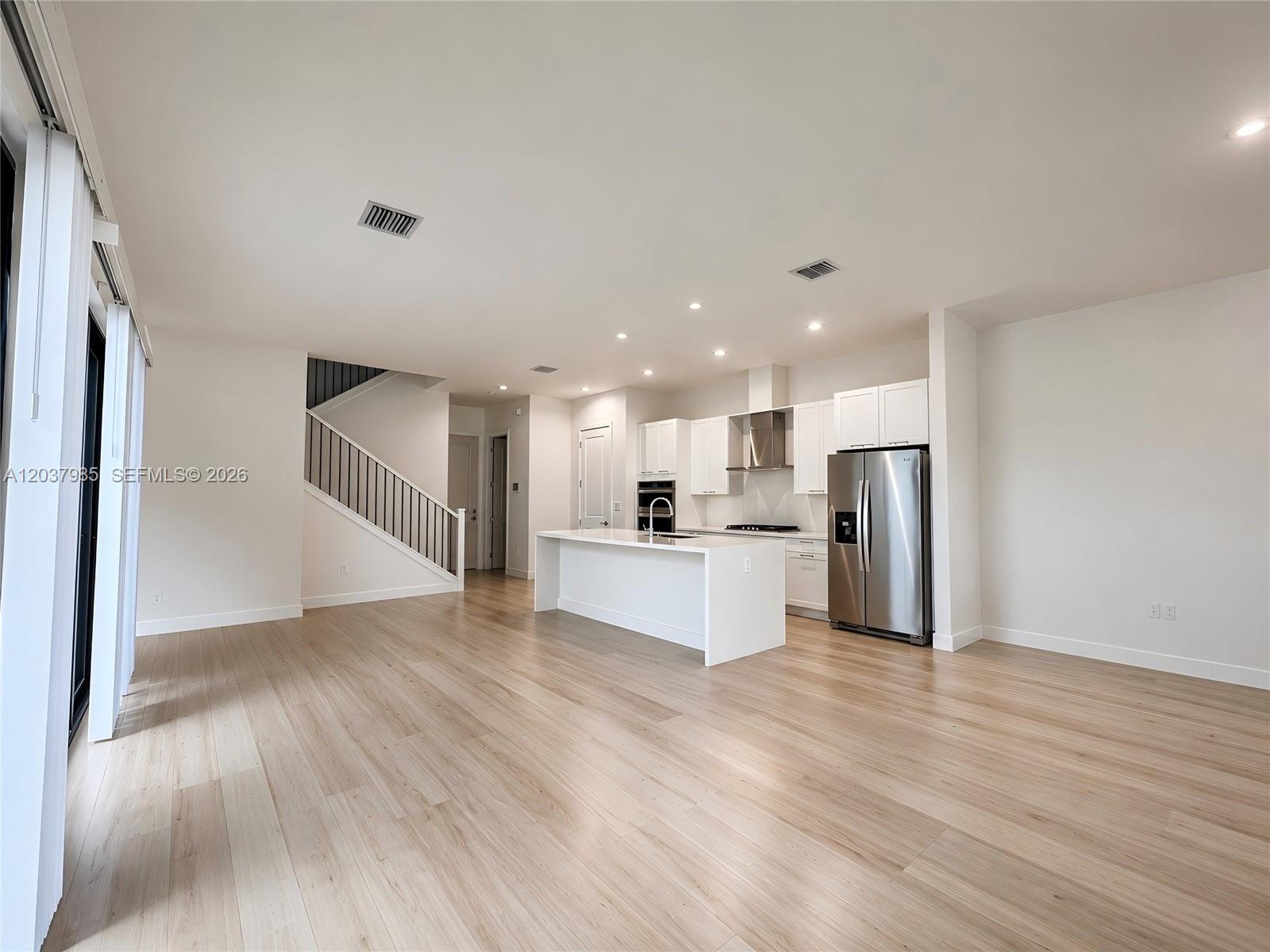 A modern kitchen with white cabinetry and an island opens into a spacious living area — 8185 NW 42nd St # 8185, Doral FL 33166, DORAL, FL