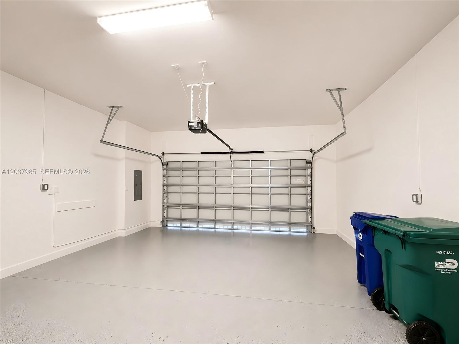 A clean, empty garage with a gray epoxy floor, white walls, and a metal door — 8185 NW 42nd St # 8185, Doral FL 33166, DORAL, FL
