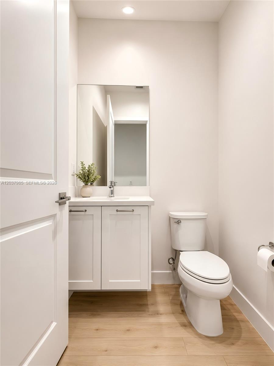 A small bathroom features a white vanity, a mirror, and a toilet on wood-look flooring — 8185 NW 42nd St # 8185, Doral FL 33166, DORAL, FL