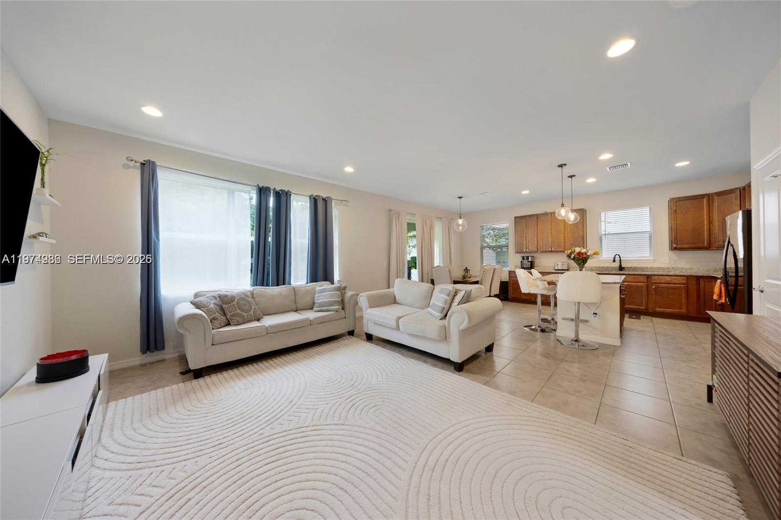 An open-concept living room and kitchen featuring light tile floors and neutral-toned furniture — 932 Banyan Dr, Hollywood FL 33021, HOLLYWOOD, FL