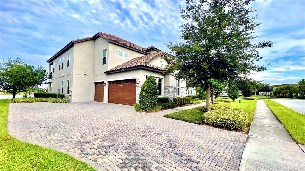 A two-story house with a brown tile roof, tan stucco siding, and a paved driveway — 7759 GREEN MOUNTAIN WAY, WINTER GARDEN, FL
