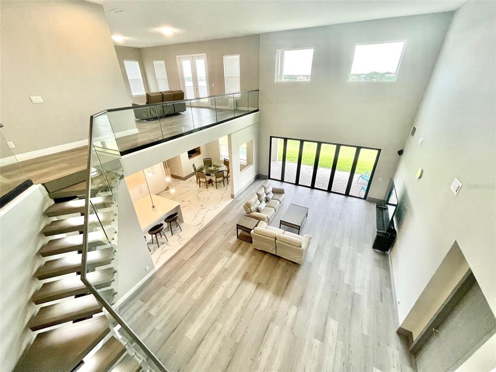 An elevated view of a modern open-concept living area with a staircase and loft — 7759 GREEN MOUNTAIN WAY, WINTER GARDEN, FL