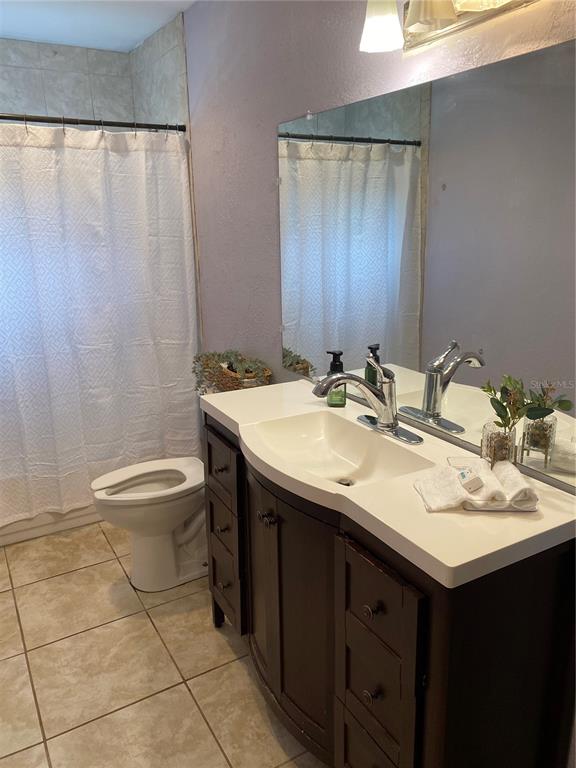 A bathroom features a dark wood vanity, white countertop, toilet, and a shower with a curtain — 1023 W GORE STREET W, ORLANDO, FL