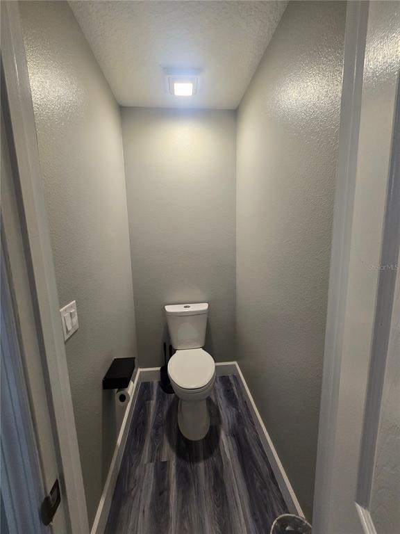 A small, narrow water closet features gray walls, wood-look flooring, and a white toilet — 510 BROOKESHIRE DRIVE, DAVENPORT, FL