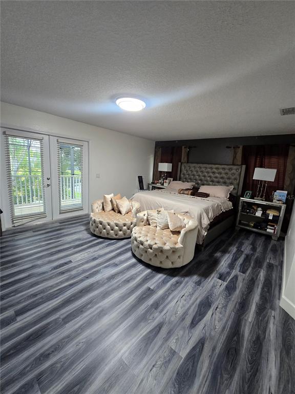 A bedroom features gray wood-look flooring, a tufted headboard, two round chairs, and balcony doors — 510 BROOKESHIRE DRIVE, DAVENPORT, FL