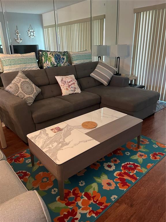 A living room features a gray sectional sofa, a marble-topped coffee table, and a floral rug — 6382 PALMA DEL MAR BOULEVARD S UNIT 222, ST PETERSBURG, FL