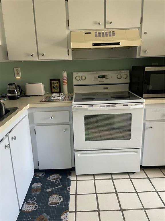 A kitchen features white cabinets, a white electric range, and a tiled floor — 6382 PALMA DEL MAR BOULEVARD S UNIT 222, ST PETERSBURG, FL