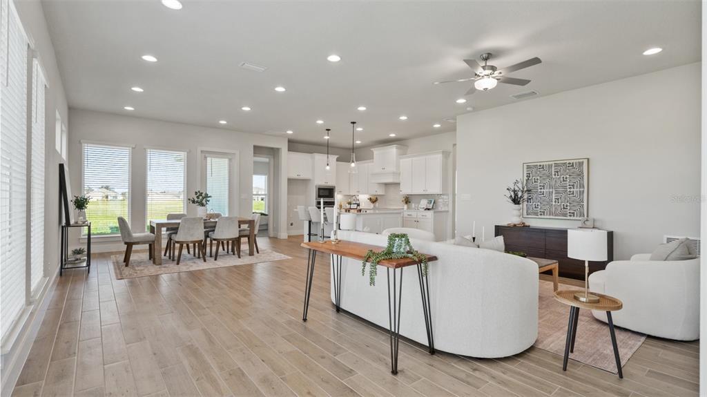 An open-concept living and dining area features white cabinetry, light wood floors, and recessed lighting — 3812 109TH STREET EAST, PALMETTO, FL