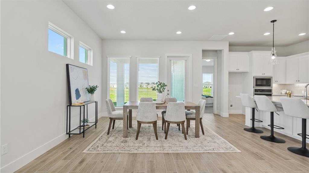 A dining area with a wooden table, chairs, and a rug sits beside a kitchen — 3812 109TH STREET EAST, PALMETTO, FL