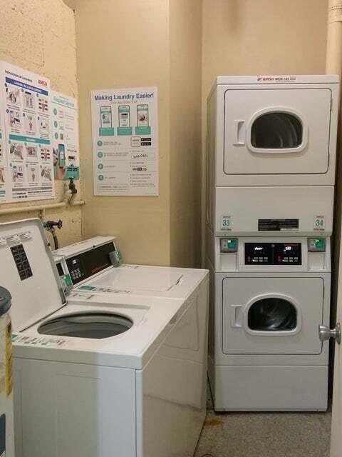 A laundry room features a top-loading washing machine and a stacked dryer unit — 480 Executive Center Drive # 4a, West Palm Beach FL 33401, WEST PALM BEACH, FL