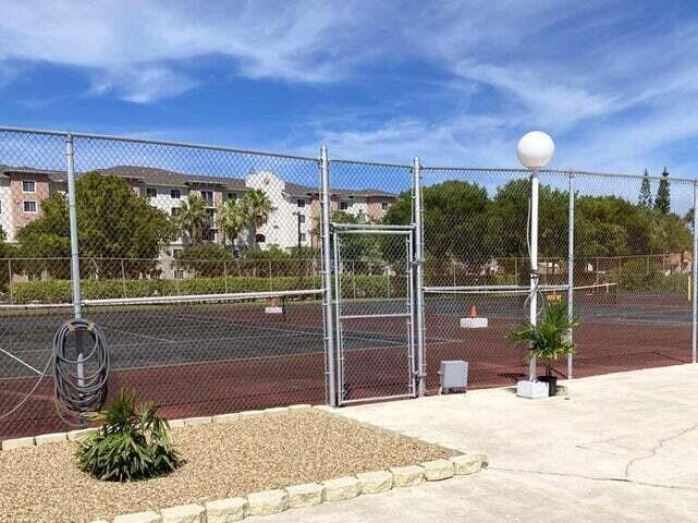 A fenced tennis court sits outdoors next to a building and a small landscaped area — 480 Executive Center Drive # 4a, West Palm Beach FL 33401, WEST PALM BEACH, FL
