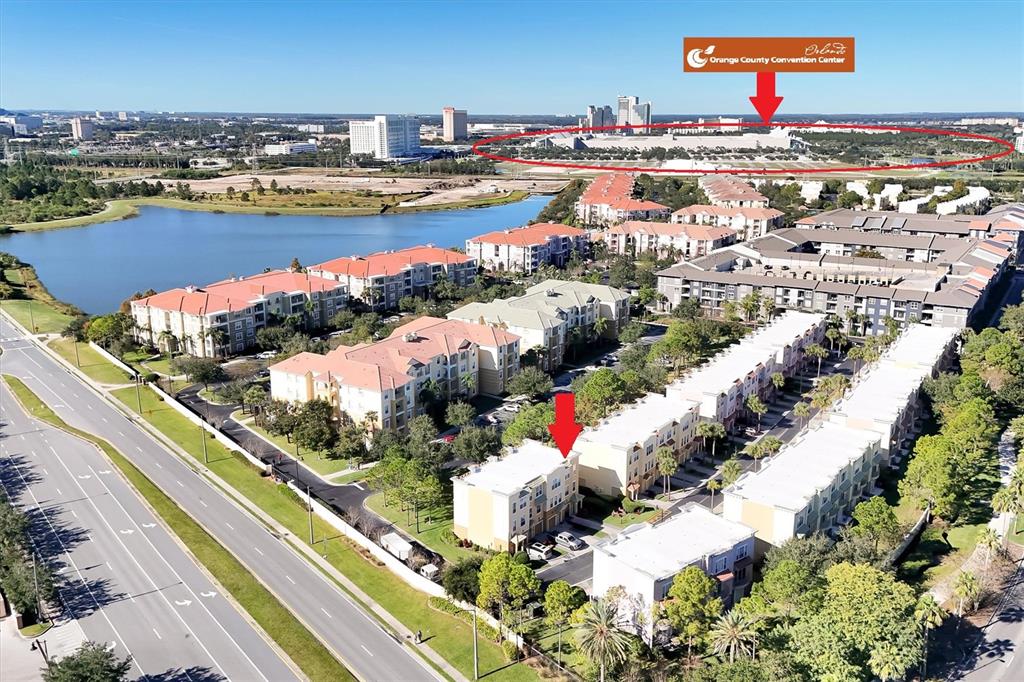 An aerial view shows a residential complex with a large convention center in the distance — 4800 TIDECREST AVENUE UNIT 172, ORLANDO, FL