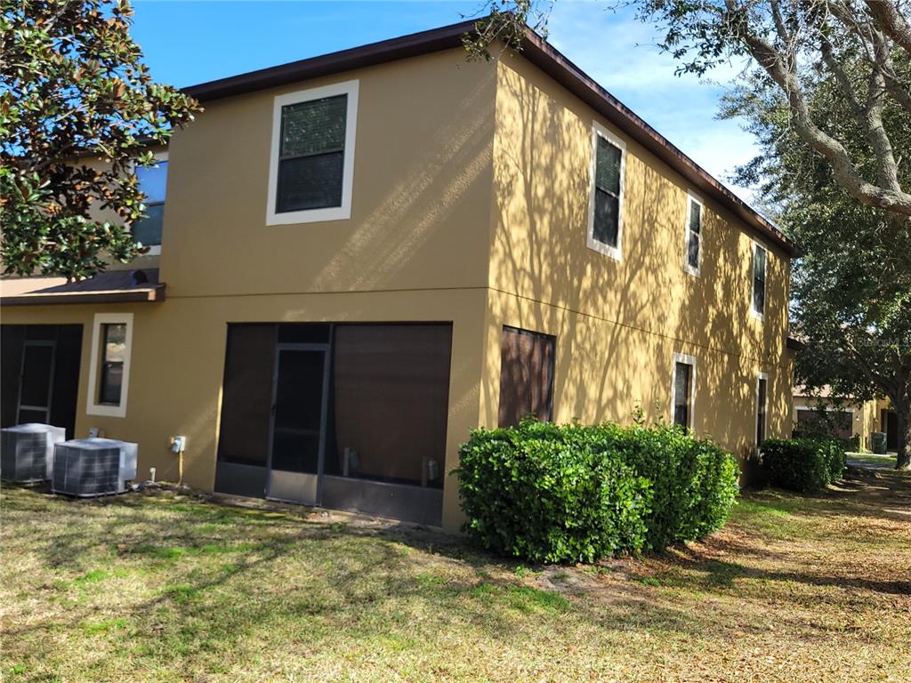 A two-story tan stucco townhouse exterior with a screened-in patio and surrounding landscaping — 2319 ALOHA BAY COURT, OCOEE, FL