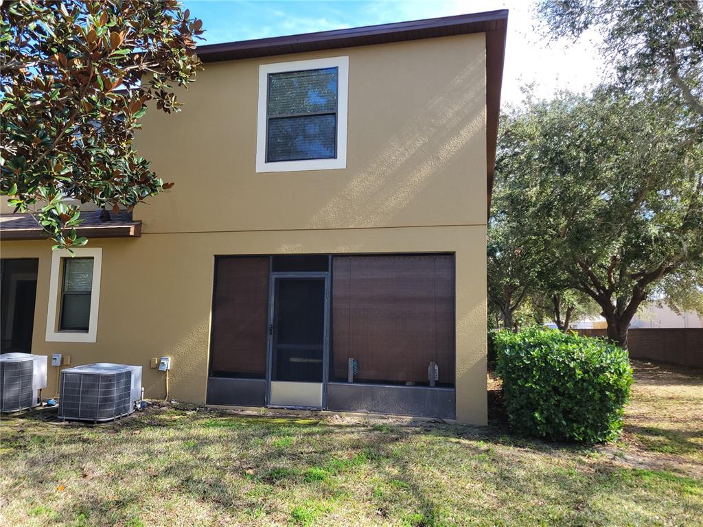 The exterior of a two-story tan house features a screened-in patio and two air conditioning units — 2319 ALOHA BAY COURT, OCOEE, FL