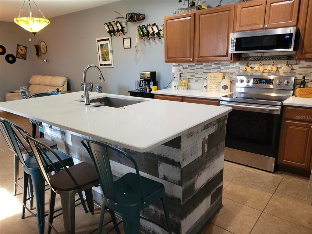 A kitchen features a white-topped island with a rustic wood base and metal bar stools — 2319 ALOHA BAY COURT, OCOEE, FL