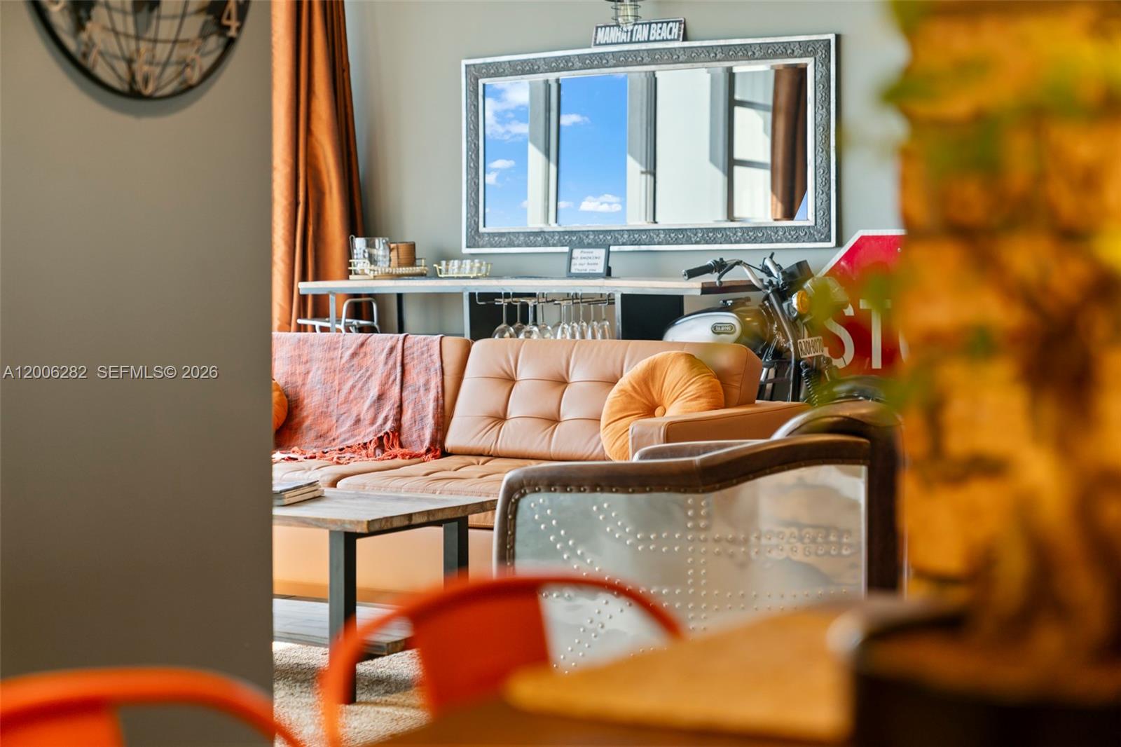 A living room features a tan leather sofa, a motorcycle, and a wall-mounted mirror — 1720 Harrison St # 1725, Hollywood FL 33020, HOLLYWOOD, FL