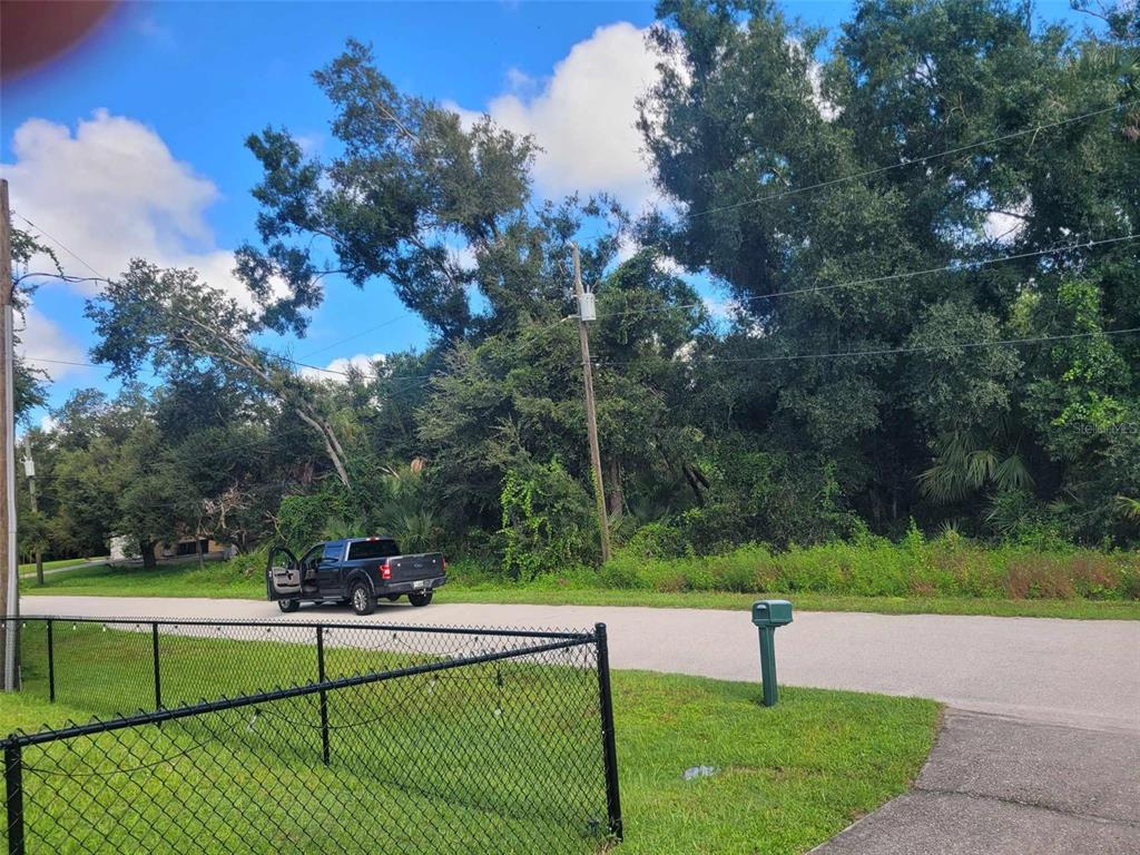 A black pickup truck is parked on a road in front of a wooded lot — APRIL AVENUE, NORTH PORT, FL