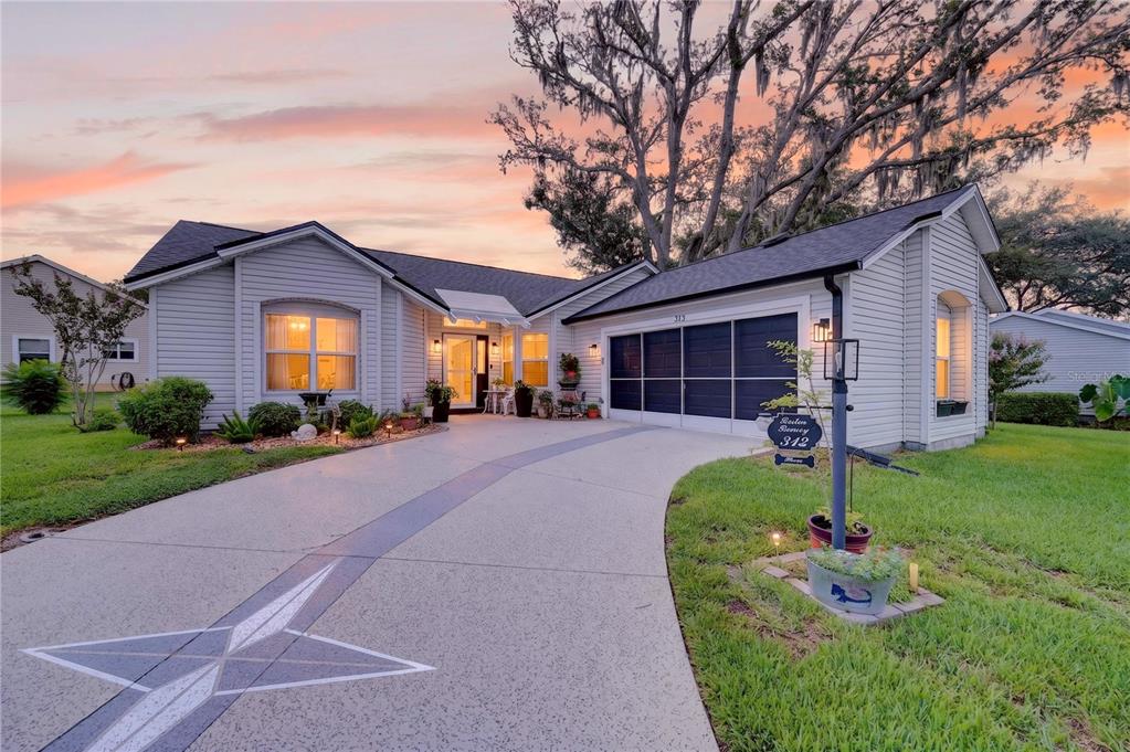 A single-story house with light siding, a curved driveway, and a large star design — 313 GONZALES PLACE, LADY LAKE, FL