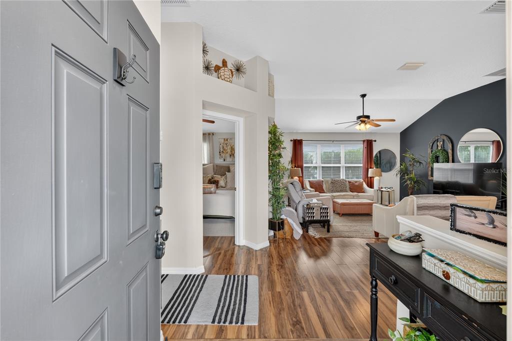 A view from an entryway into a living room with wood-look flooring and dark walls — 313 GONZALES PLACE, LADY LAKE, FL
