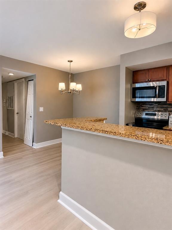 A dining area with a chandelier opens into a kitchen featuring brown cabinets and countertops — 5124 CONROY ROAD UNIT 17, ORLANDO, FL