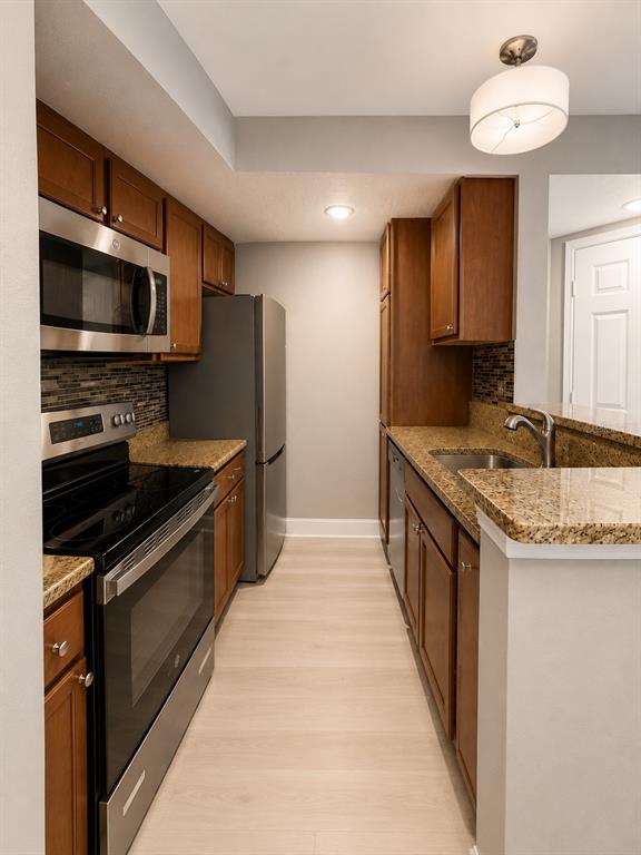A kitchen features wood cabinets, stainless steel appliances, granite countertops, and a tiled backsplash — 5124 CONROY ROAD UNIT 17, ORLANDO, FL