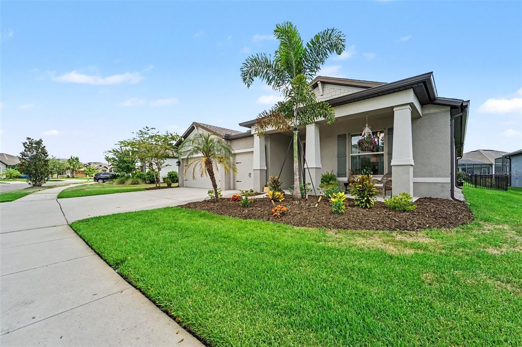 An open-concept living room and kitchen featuring a large sectional, area rug, and island seating — 7756 YALE HARBOR DRIVE, WESLEY CHAPEL, FL